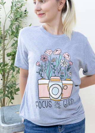 Woman wearing a heather grey Focus on the Good Camera with Wild Flowers graphic tee