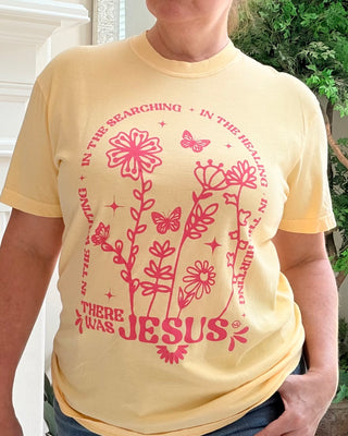 Person wearing a yellow t-shirt with pink floral design and text.