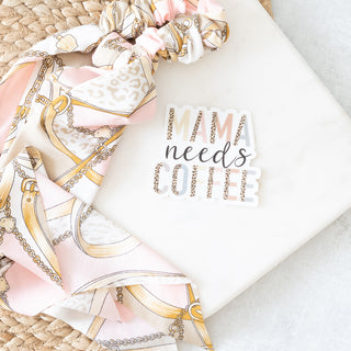 Scrunchie with gold and pink chain print scarf next to a sticker that says MAMA needs COFFEE in leopard print and script font