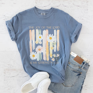 Blue t-shirt with The Joy of the Lord is My Strength Neh 8:10 text and floral graphic next to jeans and white shoes