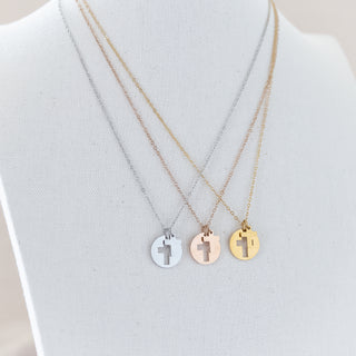 Three necklaces with cross pendants on a white stand