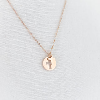 Rose gold necklace with a round pendant on a light gray background