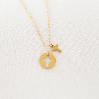 Gold necklace with two cross pendants on a light gray background