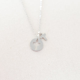 Silver necklace with a round pendant and 'X' charm on a white background
