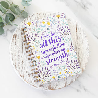 I Can Do All This Through Him Who Gives Me Strength journal with floral pattern on a white wooden board