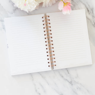 Open Love Is Patient Love Is Kind spiral wire bound ivory journal on a marble surface with flowers