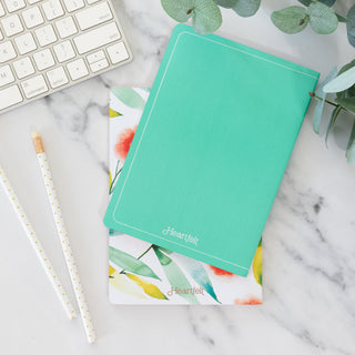 Shine Your Light Orange Blossoms set of two blank notebooks on a marble desk with keyboard and pencils