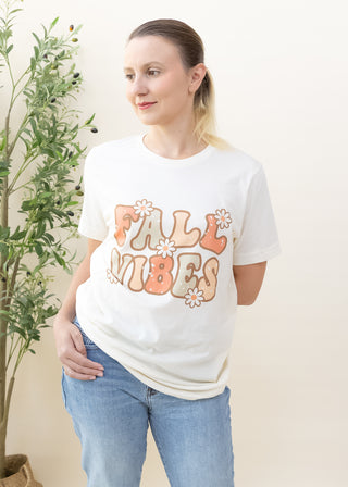 Woman wearing cream Fall Vibes Retro Daisies graphic tee with blue jeans