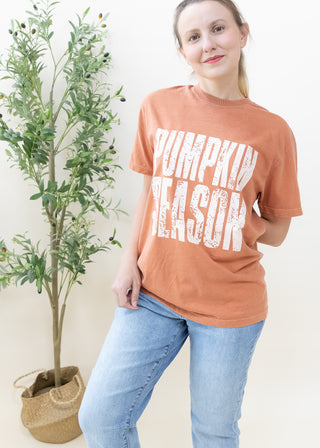 Woman wearing a yam colored Pumpkin Season graphic tee with distressed white lettering