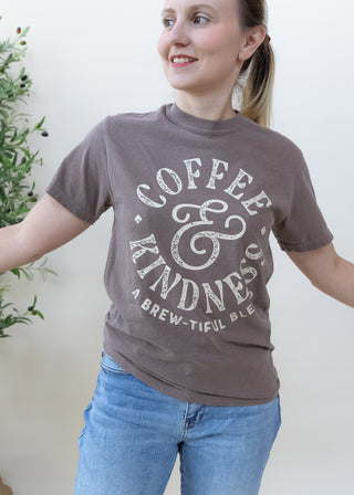 Woman wearing a brown Coffee and Kindness A Brew-tiful Blend graphic t-shirt
