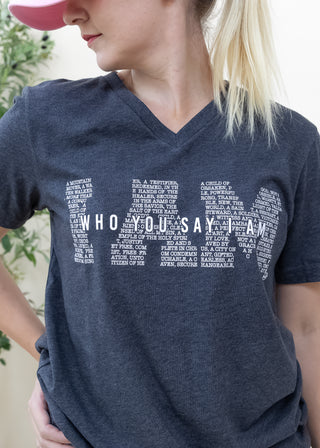 Person wearing a heather black I Am Who You Say I Am graphic tee with white text