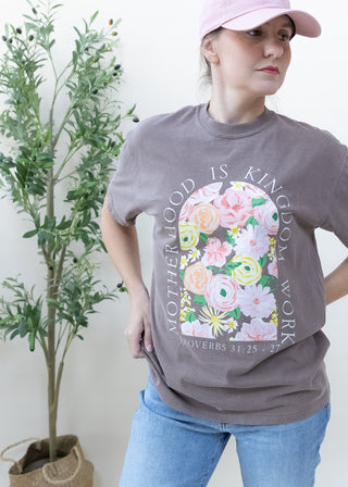 Woman wearing light chocolate brown Motherhood Is Kingdom Work Proverbs 31:25–27 graphic tee