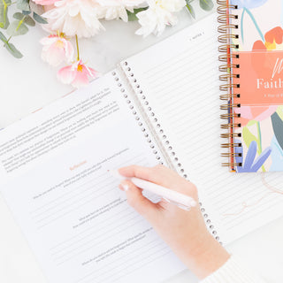 Hand writing in The Bible in A Year A 52-Week Journey Through God's Word planner with floral decor