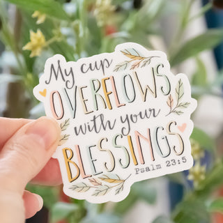 Hand holding My Cup Overflows with Your Blessings Psalm 23:5 Sticker with floral design in Christian Faith-based Boutique setting