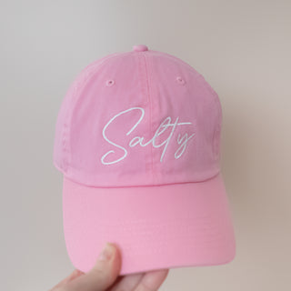 Salty in Script Writing Bright Pink Baseball Cap with white embroidered text held against neutral background