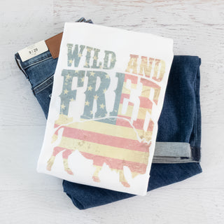 White short sleeve Wild & Free Graphic Tee folded on dark denim jeans, styled for Christian Faith-based Boutique.