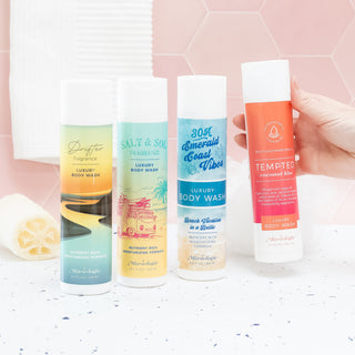 Four Mixologie luxury body wash bottles in various scents displayed on a bathroom counter