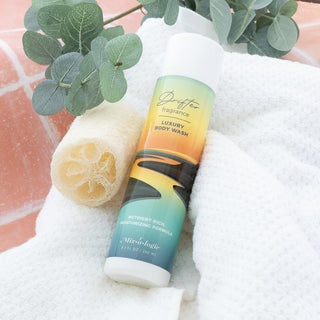 Mixologie Drifter luxury body wash bottle on a white towel with a loofah and eucalyptus sprig
