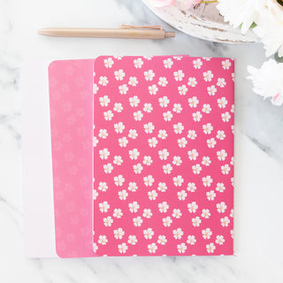 Pink and floral scripture set of three blank notebooks with a pen on a marble surface