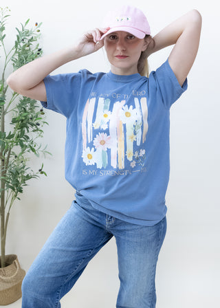 Woman wearing blue t-shirt with The Joy of the Lord is My Strength Neh 8:10 floral graphic and pink baseball cap