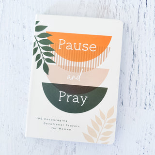 Book titled 'Pause and Pray' with leaf designs on a light wooden surface