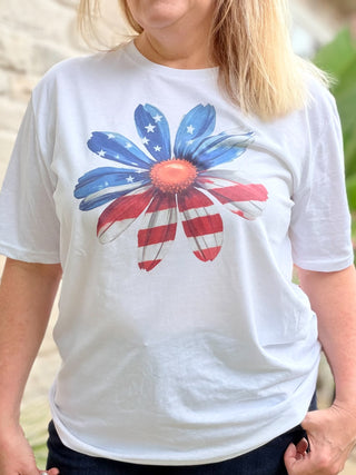 Person wearing a white t-shirt with a colorful flower design featuring red, blue, and white colors.