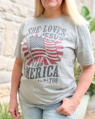 Person wearing a gray t-shirt with 'She Loves Jesus and America too' design.