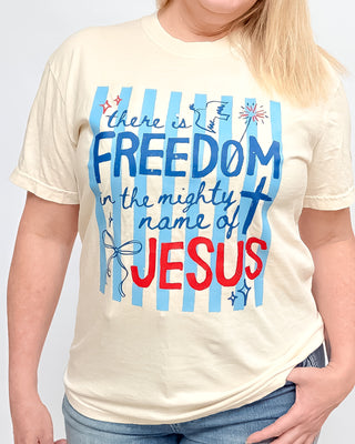 Person wearing a t-shirt with 'There is freedom in the mighty name of Jesus' text design.