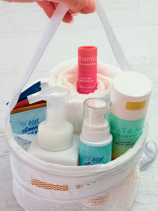 Dorm Room Essentials Mixologie Bundle containing body wash perfume oil and toiletries in a white mesh caddy