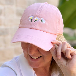 Woman wearing a Three Summer White Flowers Pink Baseball Cap smiling and adjusting the brim outdoors