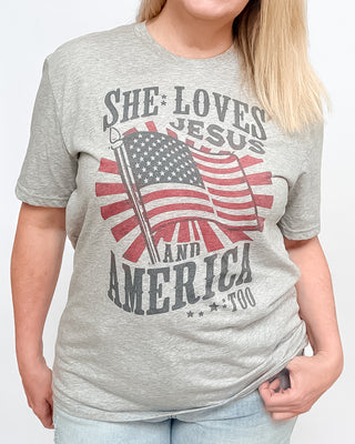 Gray t-shirt with 'She Loves Jesus and America Too' graphic design on a white background