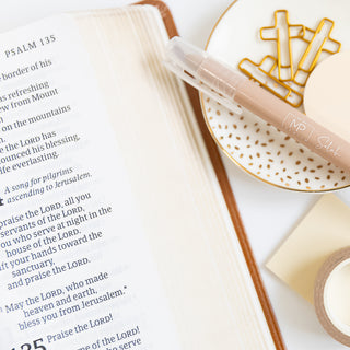 Open Bible showing Psalm 135 with highlighter and gold cross-shaped paper clips on white speckled dish nearby